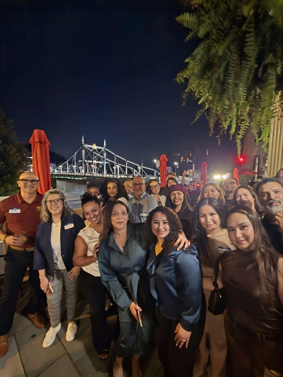 Grupo completo de asistentes al segundo evento de Business Spotlight, con el puente iluminado de fondo